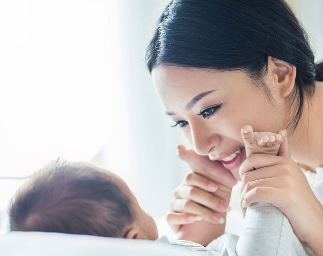 Mother holds her baby’s feet to her face