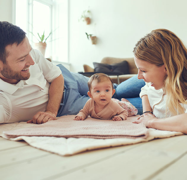 Father and mother smile at their baby between them