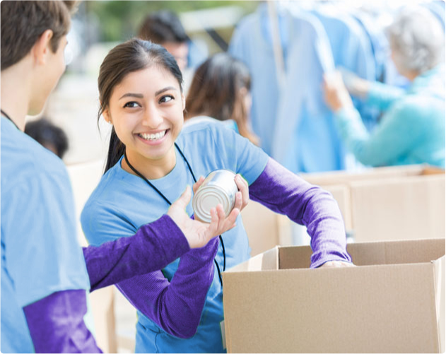 Young woman takes can donation while packing box.