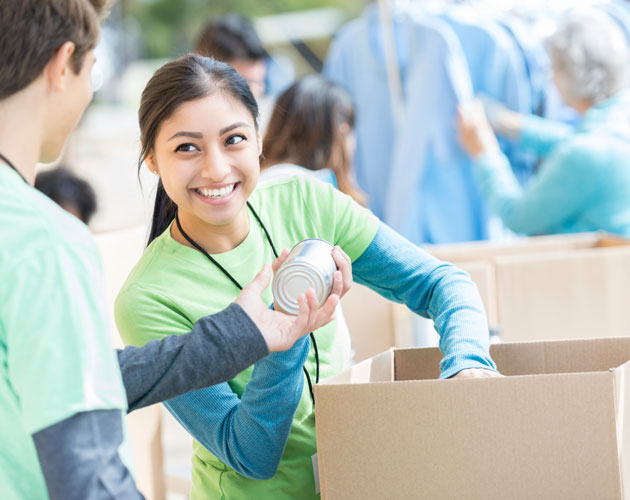 Young woman takes can donation while packing box