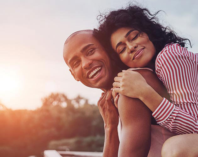 A woman hugs a man from behind