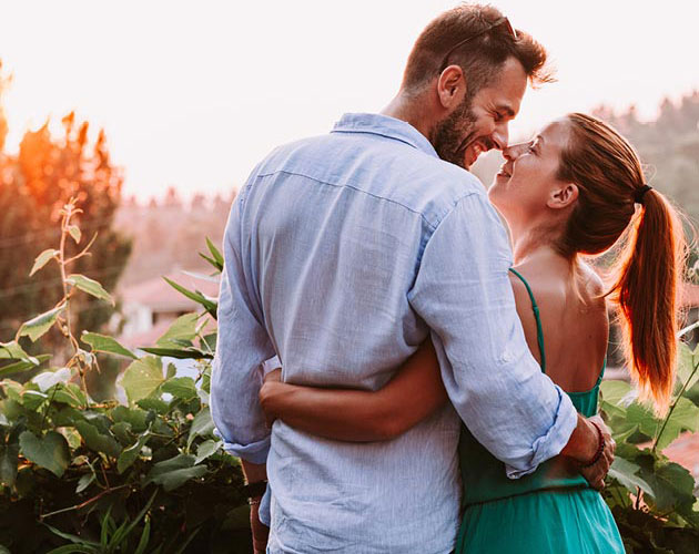 A young couple touch noses while smiling at each other