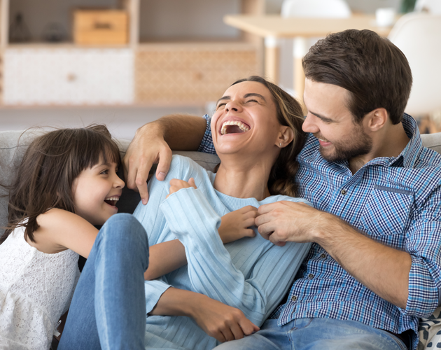 Happy family laughing on a couch.