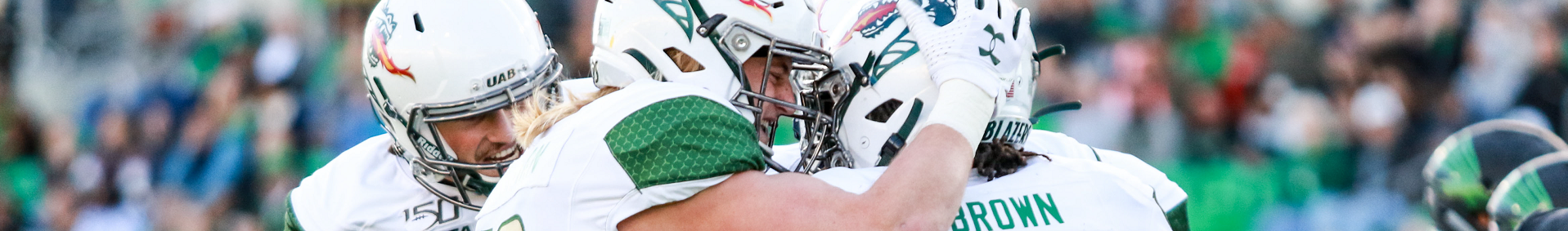 UAB football players celebrate on the field.