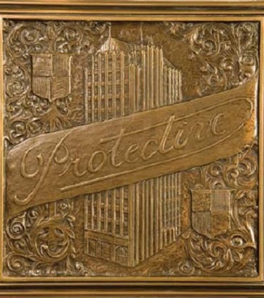 A golden memento reading Protective across a drawing of the old Protective Life building in downtown Birmingham. 