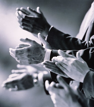 A black and white photo of businessmen clapping as if to celebrate. 