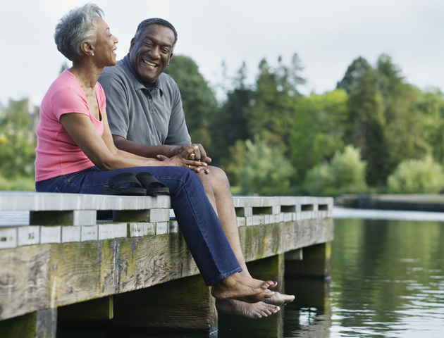 Older African-american couple sitting on dock laughing
