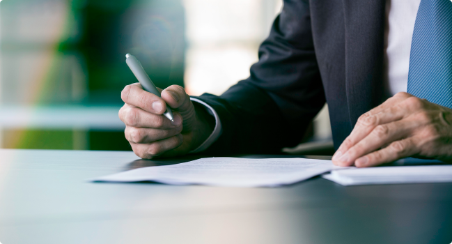 Closeup of a man's hands as he holds a pen while reviewing Protective's Code of Conduct.