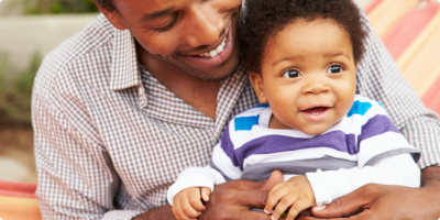 Young father looking at toddler son in his lap