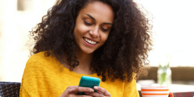 Young woman smiling as she uses her smart phone
