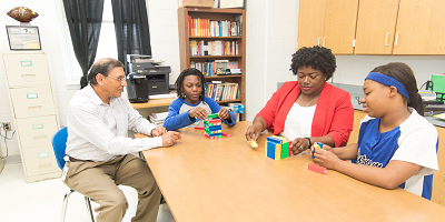 Protective employees sitting at table with young students