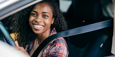 African American teen smiling while at the wheel of a car.